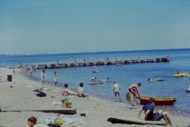 Swimmers on beach and long concrete pier